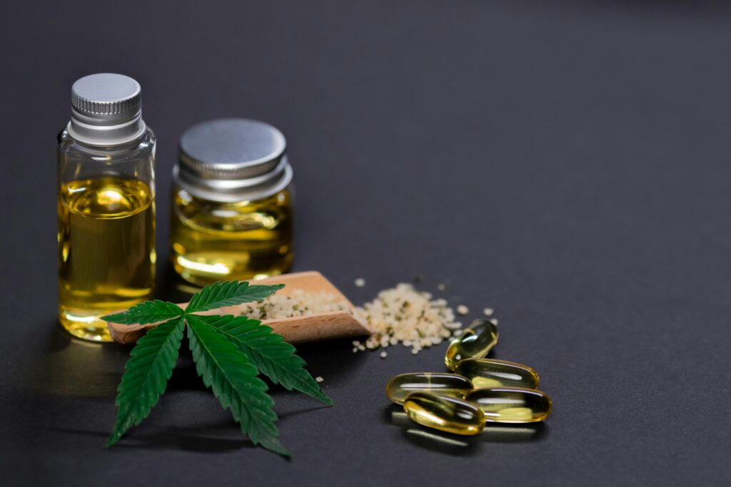 
A picture of CBD products like pills and oils and crumbled marijuana next to a marijuana leaf